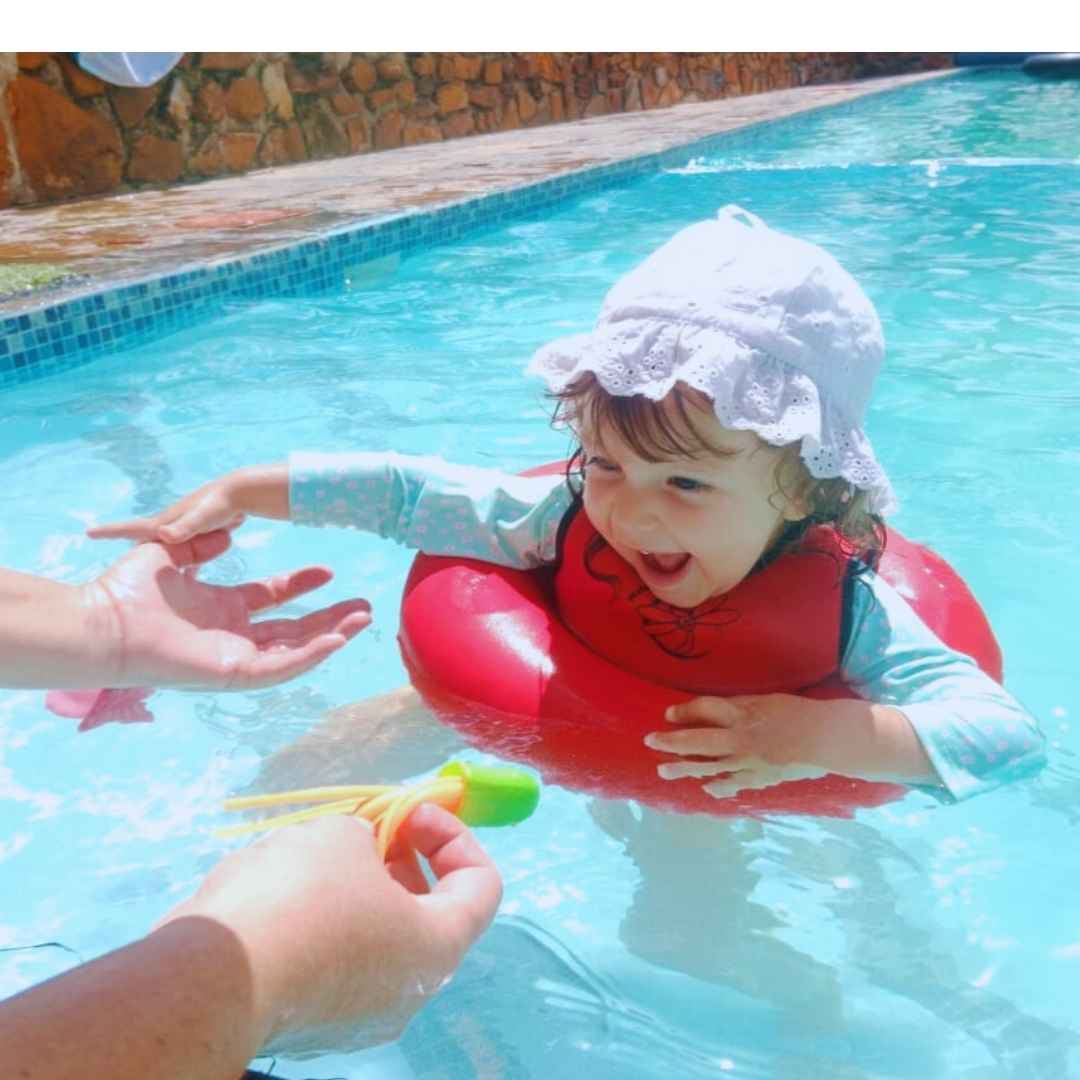 Baby girl with lace hat playing in the pool